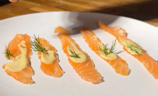 Gravlax de saumon au gin bota sans alcool et sauce sucrée sur une assiette blanche