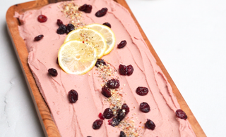 planche de bois recouverte de houmous au canneberge avec comme décoration des canneberges séchées et des tranches de citron