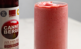Verre de smoothie fraise, framboise et canneberge avec une bouteille de jus concentré de canneberge sans sucre par CANNE BERGE