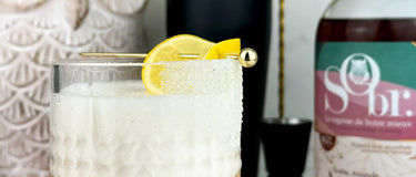 Verre d'amaretto sour sans alcool avec une bouteille d'amaretto érable et amande sans alcool de SObr