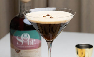 Verre de martini rempli d'un espresso martini sans alcool. Une bouteille d'amaretto érable et amande sans alcool par SObr.