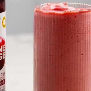 Verre de smoothie fraise, framboise et canneberge avec une bouteille de jus concentré de canneberge sans sucre par CANNE BERGE